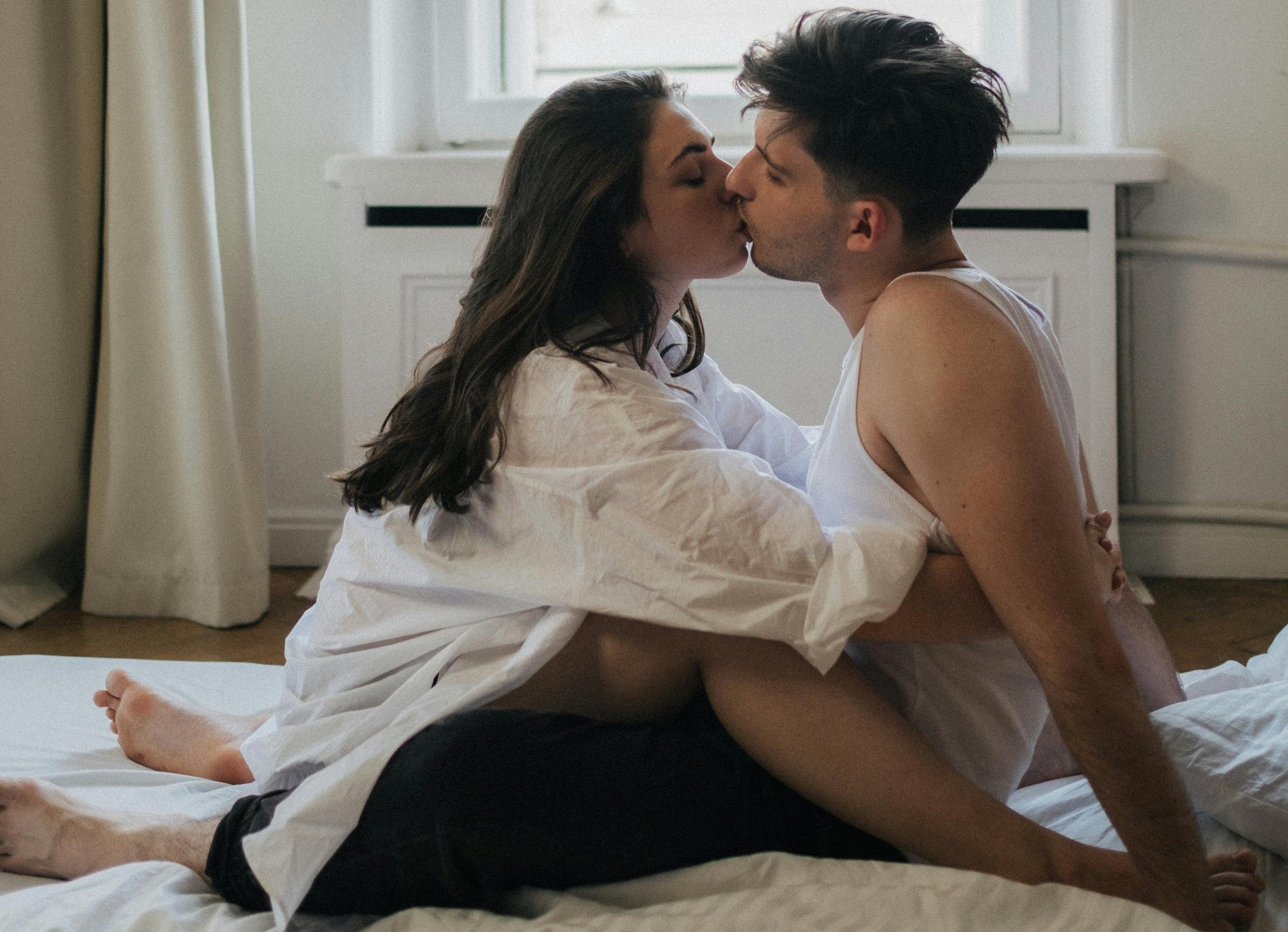 A loving couple is kissing on bed. This moment portrays the joy and satisfaction that can come from a healthy sex drive and fostering intimacy in a relationship.